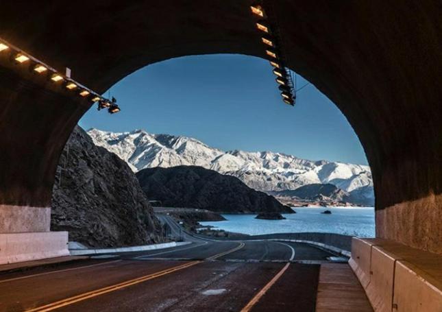a view of a road under a bridge with mountains at Open House Hostel in Mendoza