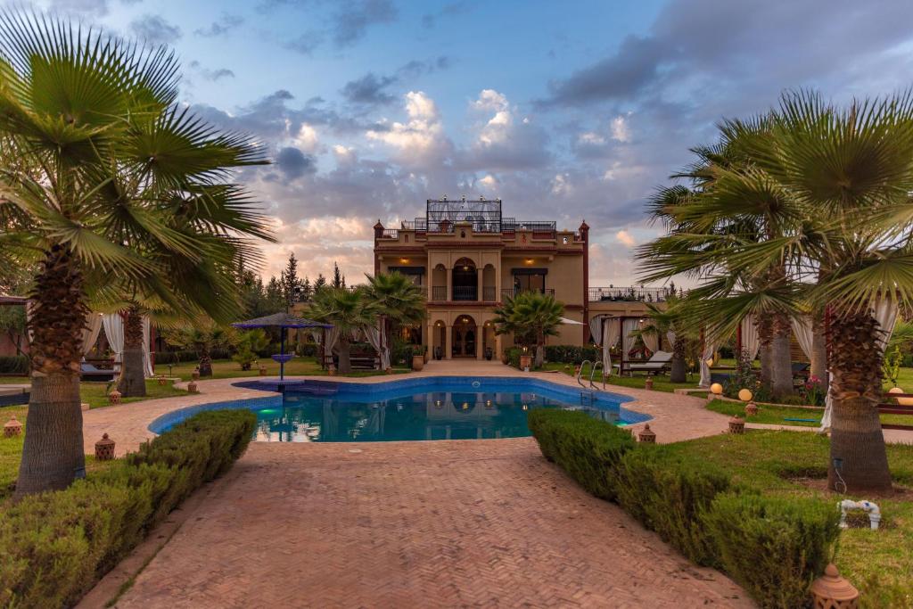 ein großes Haus mit Swimmingpool und Palmen in der Unterkunft Villa pension complète Marrakech in Marrakesch