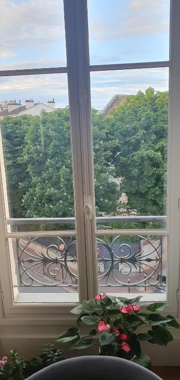 une pièce avec une fenêtre avec vue sur les arbres dans l'établissement L'élégance à proximité du centre aquatique des JO, à Levallois-Perret