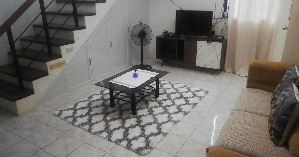 Una sala de estar con una mesa y un televisor. en La Maison transient house, en Calapan