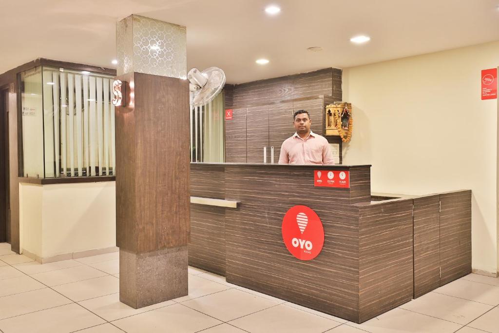 Un homme debout derrière un comptoir dans un restaurant dans l'établissement Collection O Hotel Santro, à Naroda