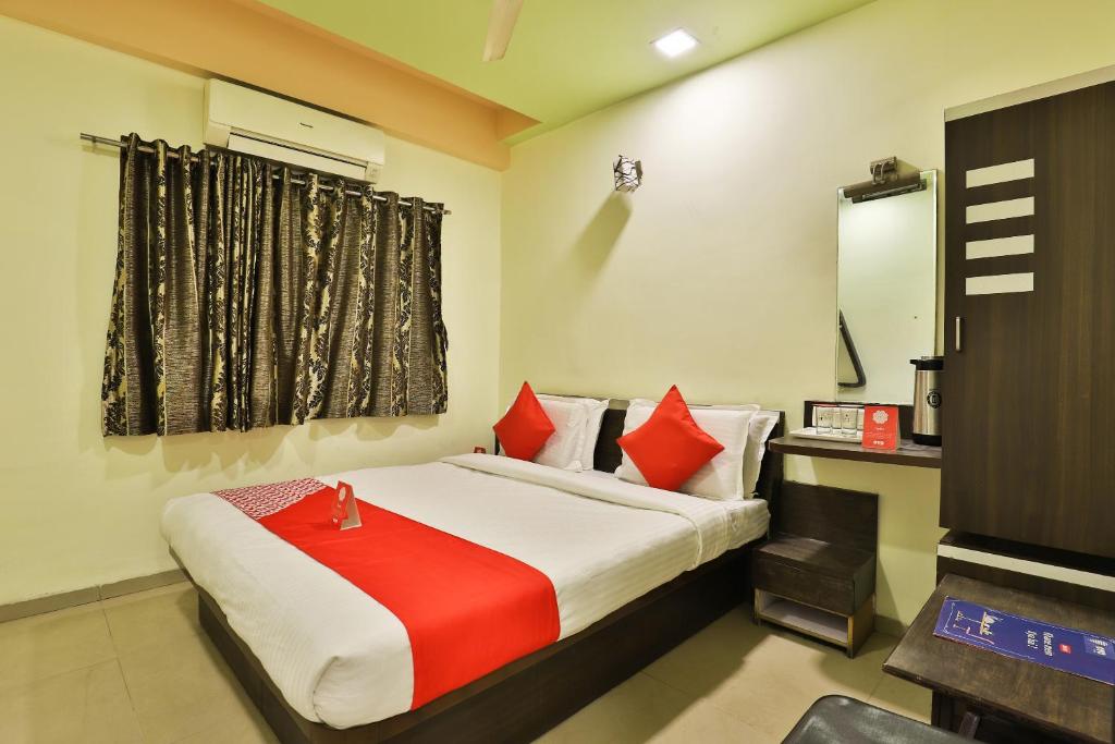 Schlafzimmer mit einem Bett mit roten Kissen und einem TV in der Unterkunft Collection O Hotel Santro in Naroda