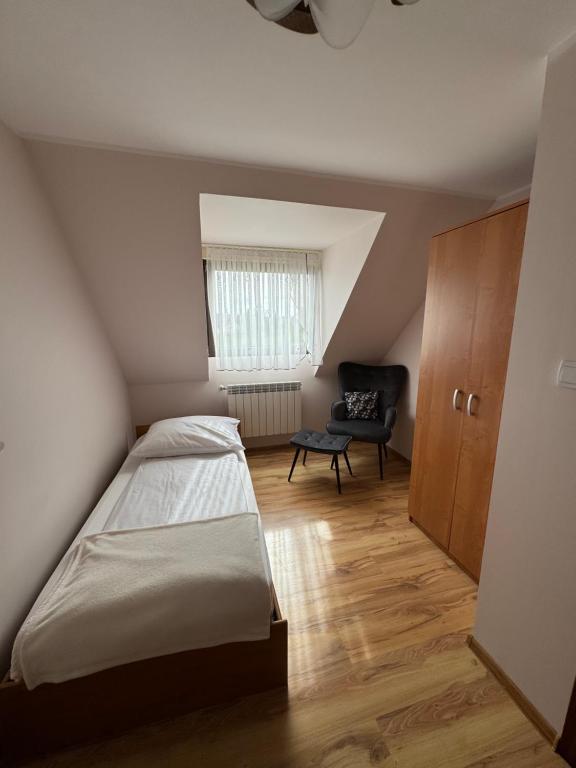 um pequeno quarto com uma cama e uma cadeira em Górski Przystanek em Mizerna