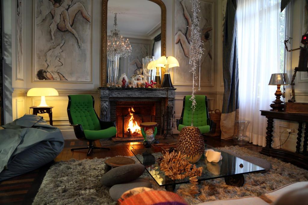 a living room with two green chairs and a fireplace at Le Grand Duc in Valenciennes