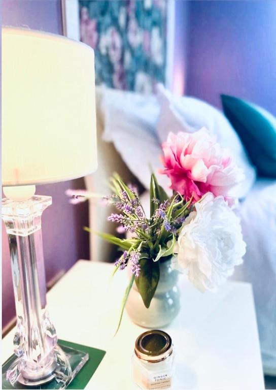a table with a lamp and a vase of flowers at JCK Tuscany Apartment in Livorno