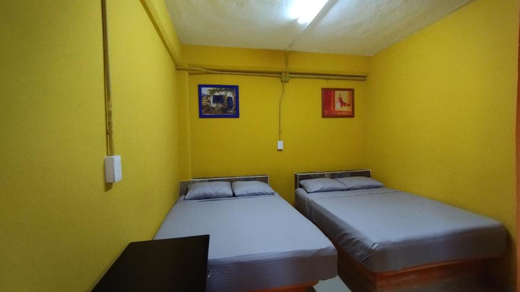 2 łóżka w pokoju z żółtymi ścianami w obiekcie NovHotel w mieście Comalcalco