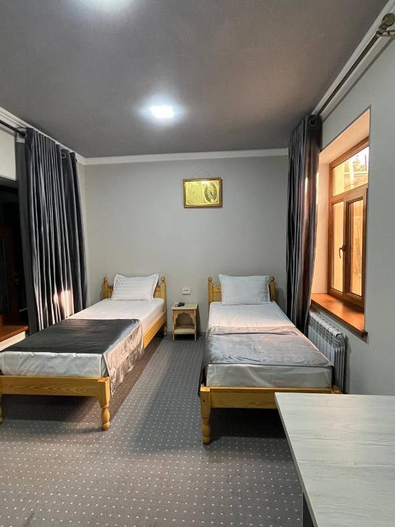 a room with two beds and a window at Bukhara Hotel Alikhan in Bukhara