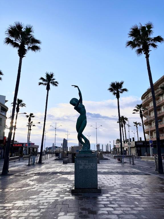 a statue of a woman standing in a plaza with palm trees at Studio côté plage tout équipé vue sur le Canigou in Canet-en-Roussillon
