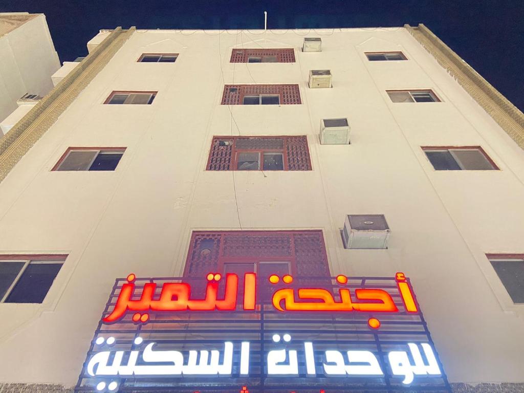 a tall white building with a sign on it at اجنحة التميز للوحدات السكنية in Medina