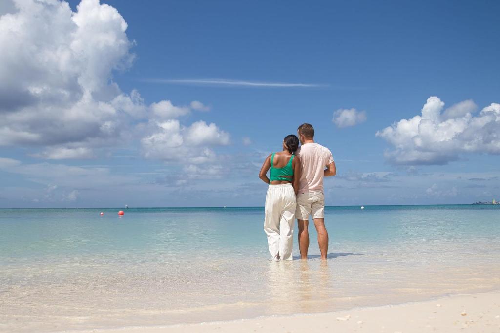 un homme et une femme debout sur une plage dans l'établissement Beach Living at Island Pine Villas 'BLJW', à George Town