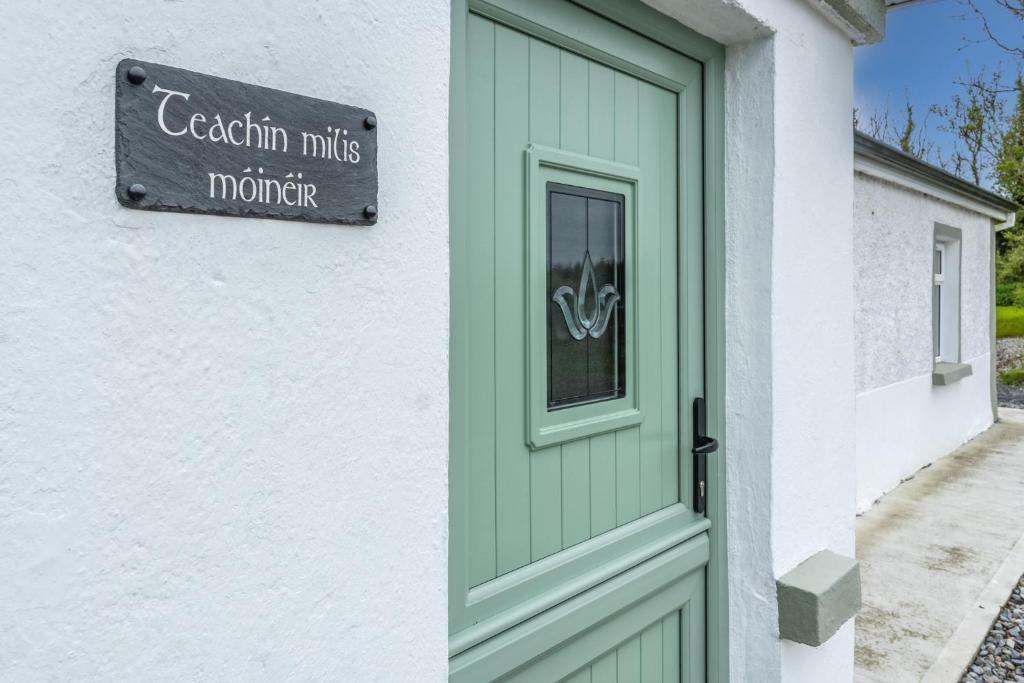 una puerta verde en un edificio blanco con un cartel en Teachin milis Moineir en Boyle