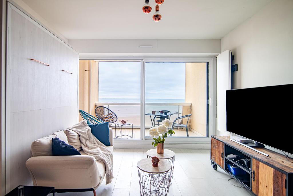 un salon avec une télévision à écran plat et un canapé dans l'établissement L'Océan à Vos Pieds Appartement Vue Panoramique La Baule, à La Baule