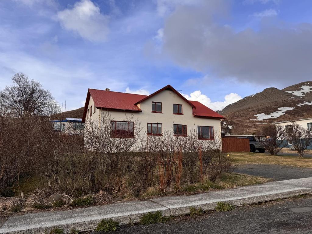 a house with a red roof on the side of a road at Guesthouse Tálknafjörður in Talknafjordur