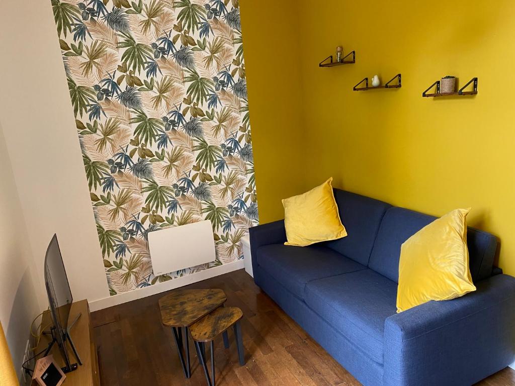 a living room with a blue couch and a yellow wall at Le Colibri - Domaine de la Houblette in Challans