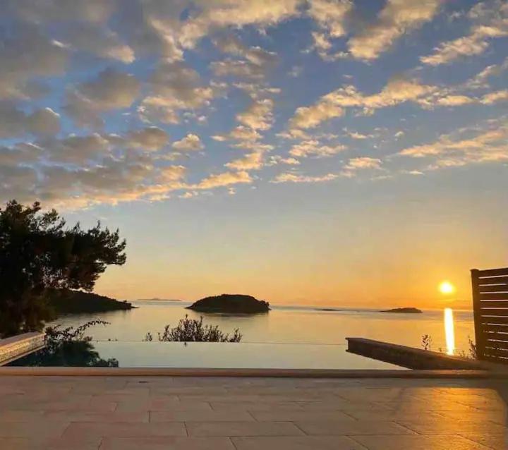 a sunset over the water with a bench in front at Mediterranean Jewel in Blato