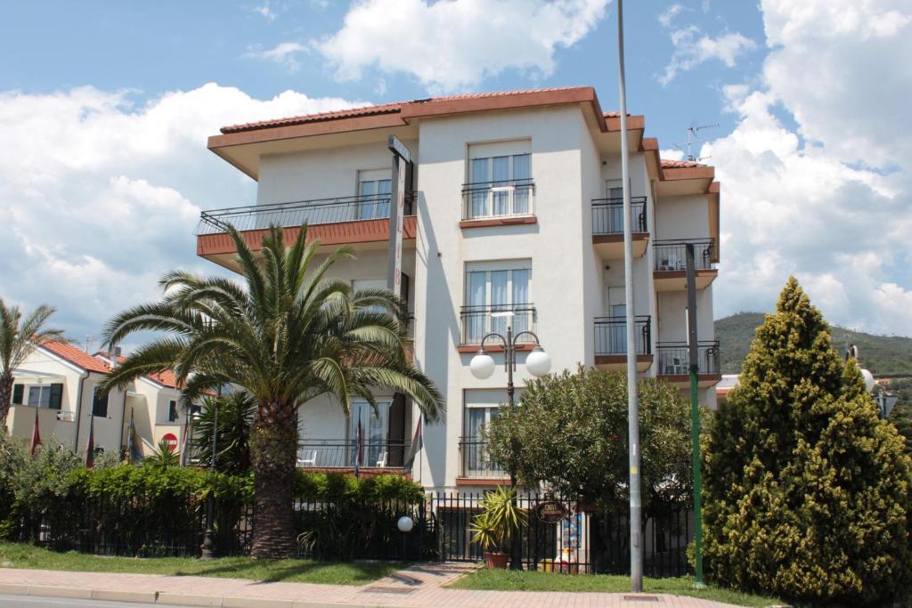 un edificio blanco con palmeras delante en Residence Colibrì Family & Bike, en Loano
