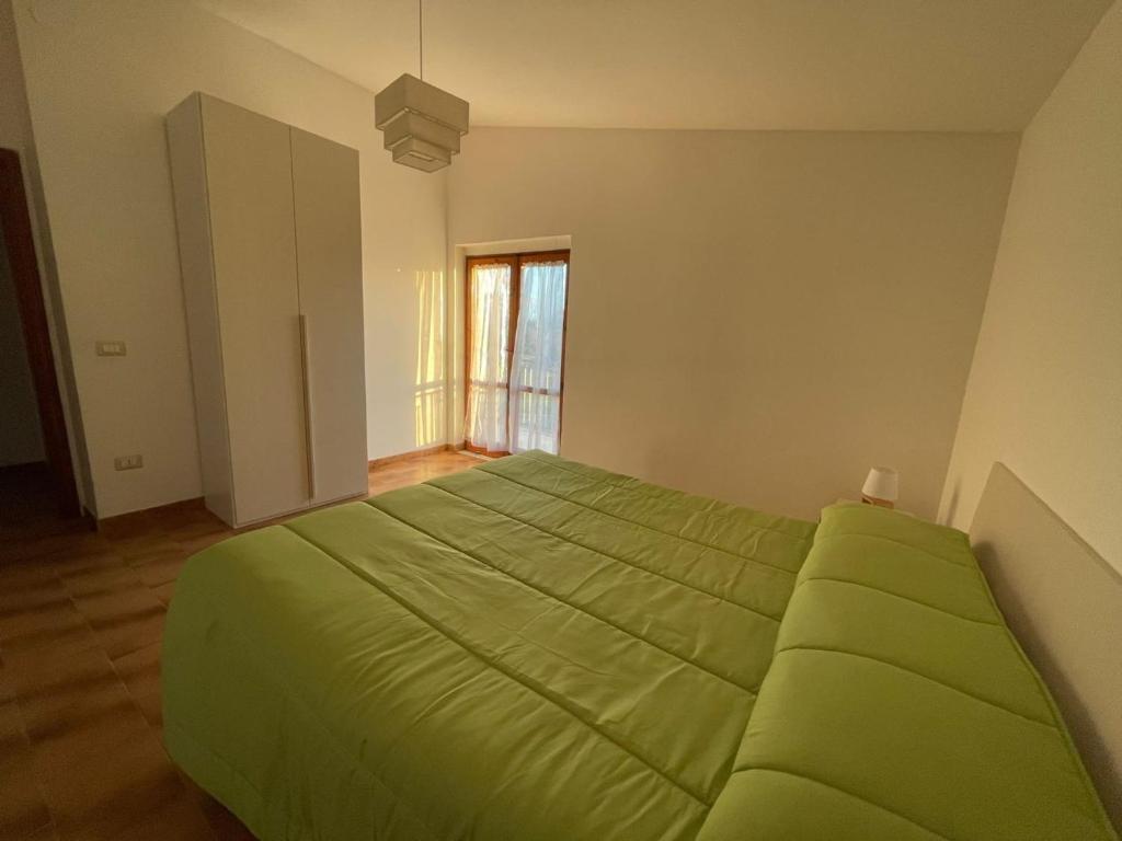 ein grünes Bett in einem Zimmer mit Fenster in der Unterkunft Parco Nonna Nina in Castellammare di Velia