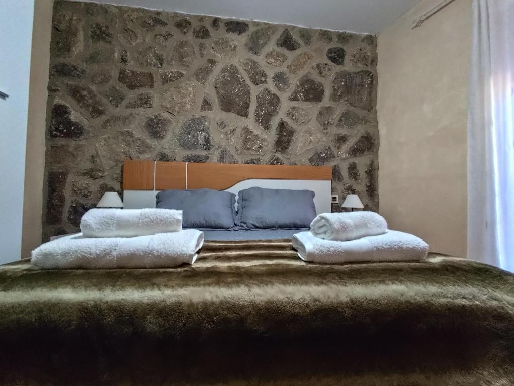 a bedroom with a large bed with a stone wall at Casa del Caño 