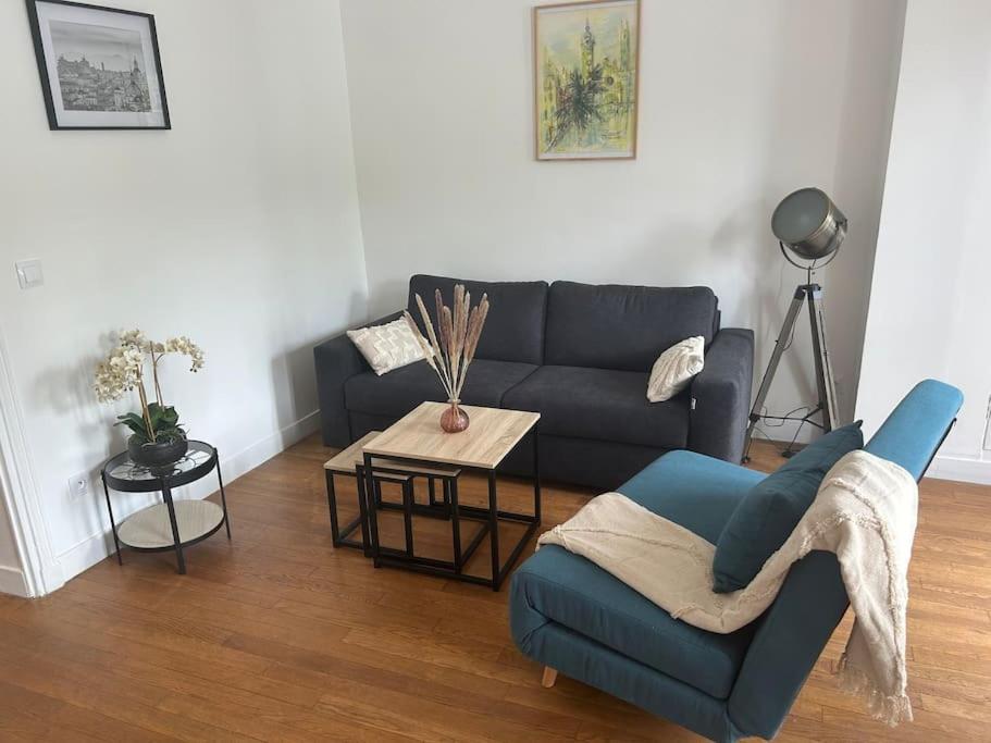 a living room with a blue couch and a table at Appartement aux portes de Paris in Saint-Mandé