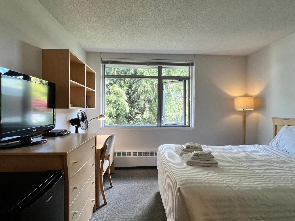 a hotel room with a bed and a television at Carey Centre on UBC campus in Vancouver