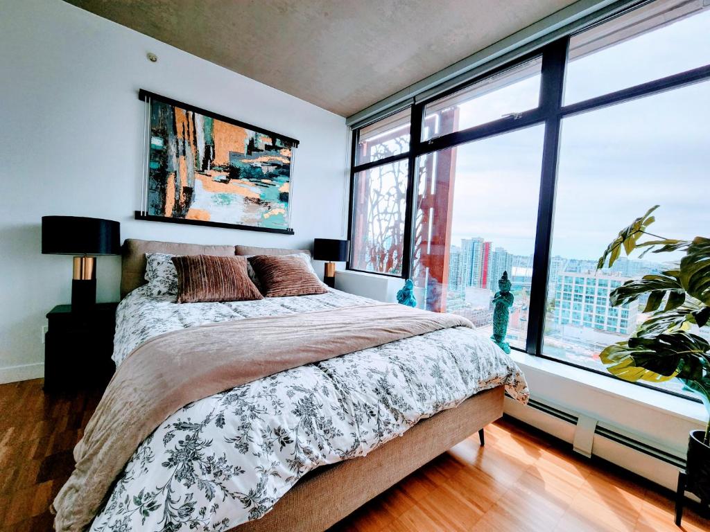 a bedroom with a large bed and large windows at Luxury Downtown Vancouver Suite in Vancouver