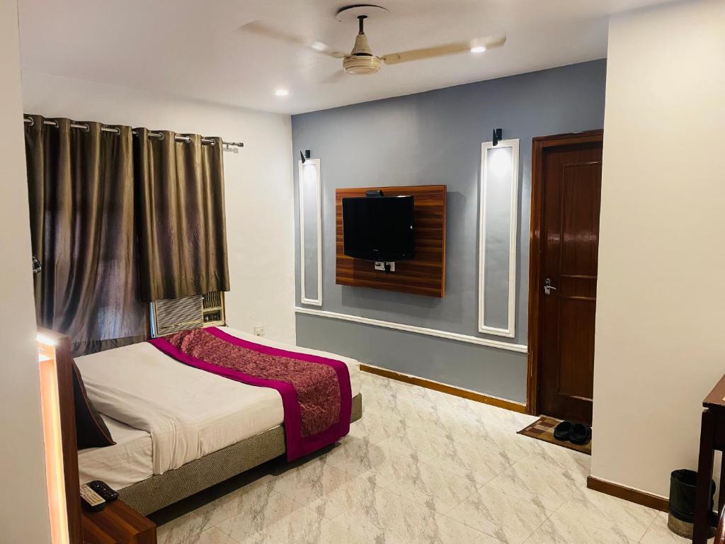 Schlafzimmer mit einem Bett und einem Flachbild-TV in der Unterkunft Royal Presidency Inn in Lucknow