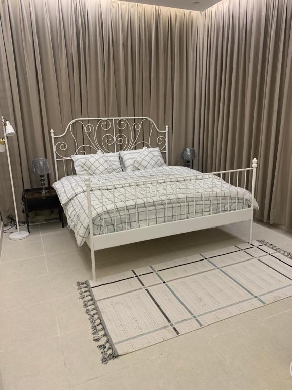 uma cama branca num quarto com cortinas em فيلا رسن em Al Hada