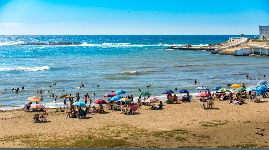 una multitud de personas en una playa con sombrillas en Résidence hadji, en Sidi Ferruch
