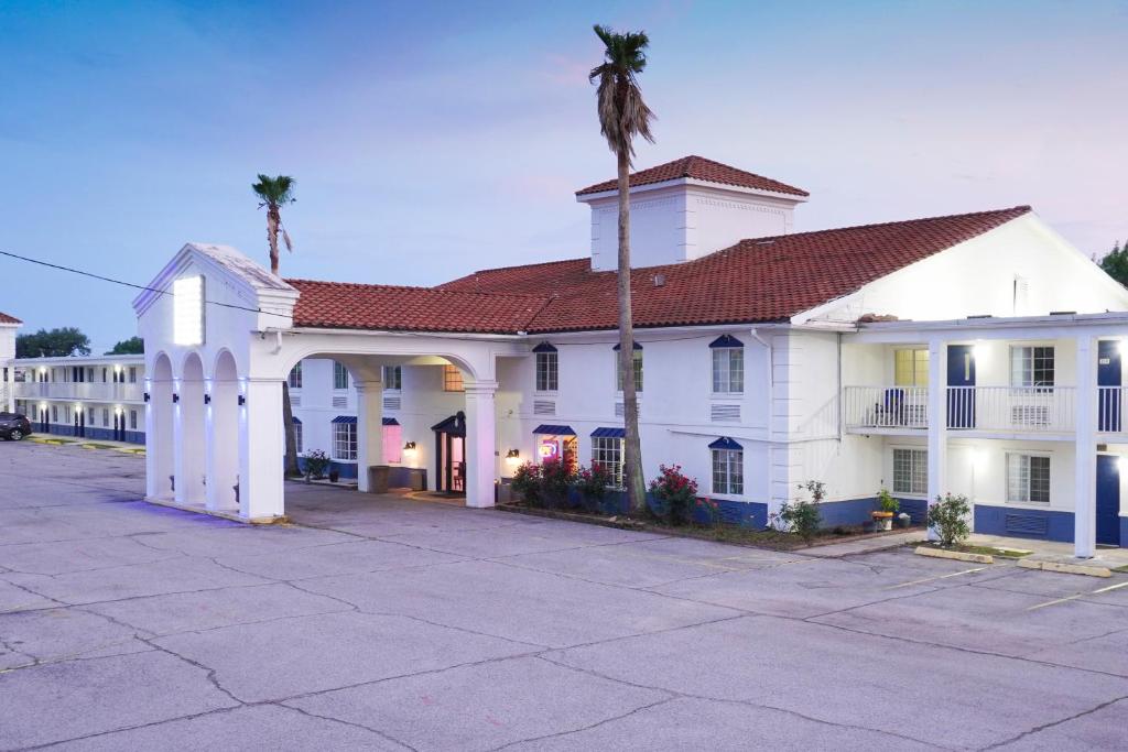 een wit gebouw met een palmboom ervoor bij Boardwalk Suites Lafayette in Lafayette