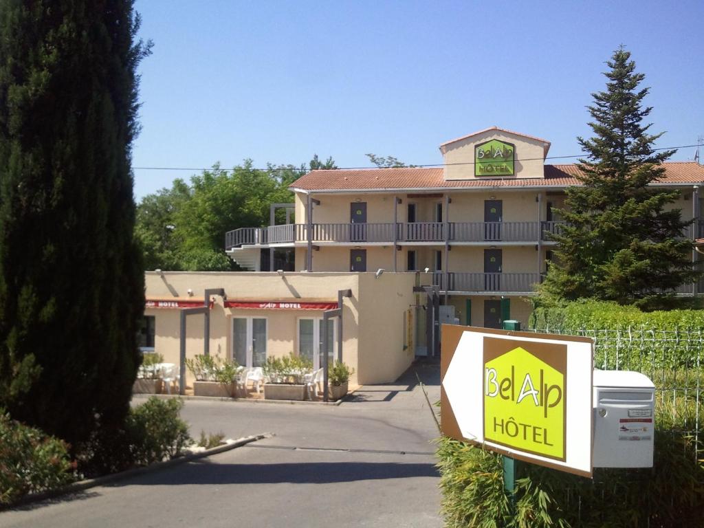 un grand hôtel avec un panneau devant lui dans l'établissement Hotel Bel Alp Manosque, à Manosque