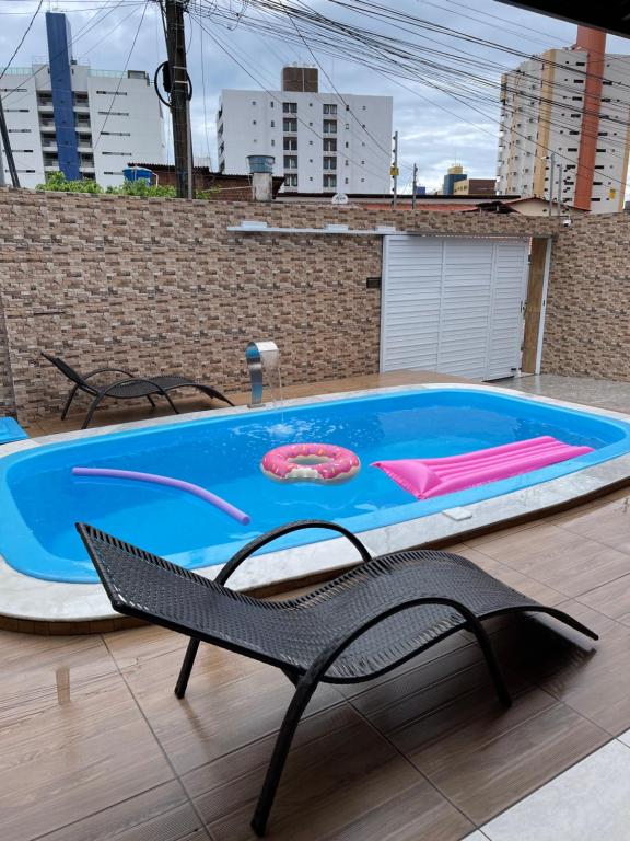 a swimming pool with a chair and a table at Casa de Férias á 400m pra Praia de Cabo Branco in João Pessoa