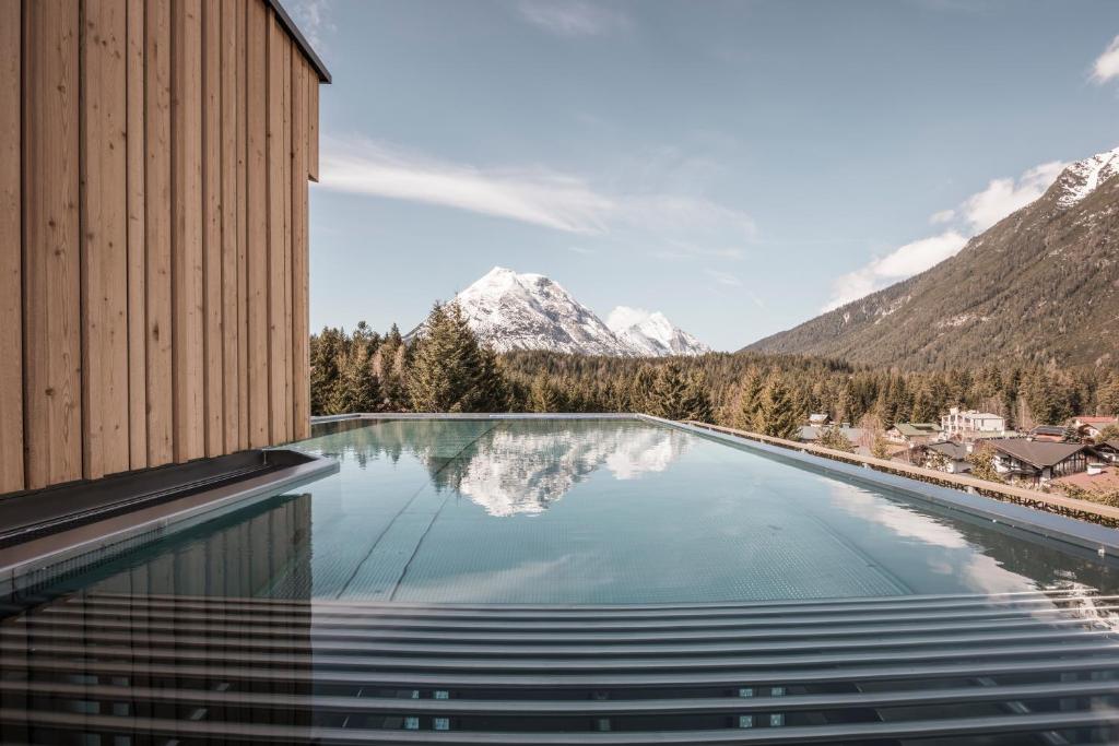 une piscine avec des montagnes en arrière-plan dans l'établissement Hotel Kristall - Adults only, à Leutasch