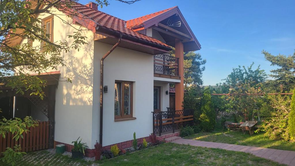 een wit huis met een balkon en een tuin bij Domek u Eli in Solec-Zdrój