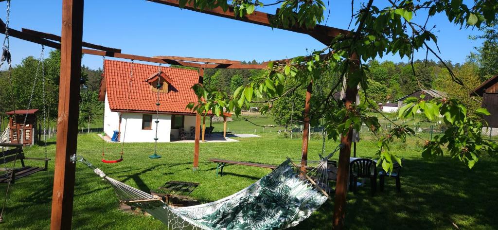 a hammock in a yard with a house at Agroturystyka Stara Huta - Domek Boho in Narol