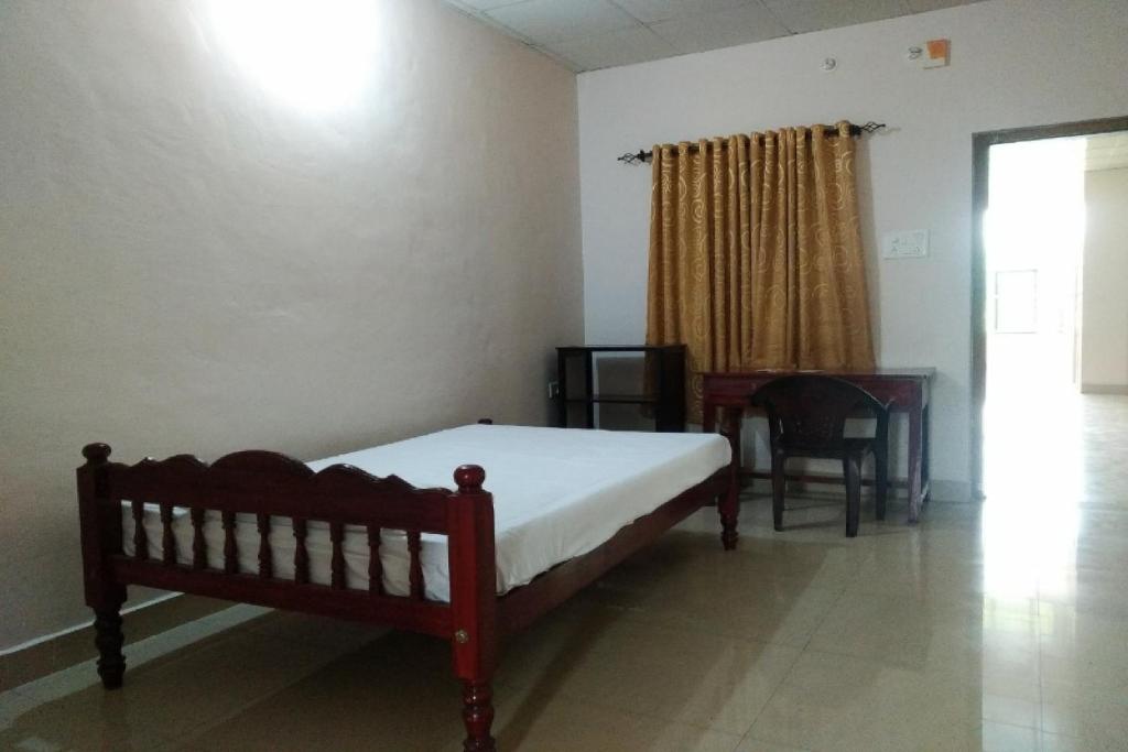 a bedroom with a bed and a table and a desk at SPOT ON Sana Tourist Home in Kollam