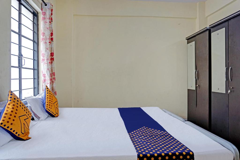 a bedroom with a bed with orange and blue pillows at SPOT ON Hotel Prakash Residency, Near Hanuman Gym Ajmera Colony, Pimpri in Chinchwad