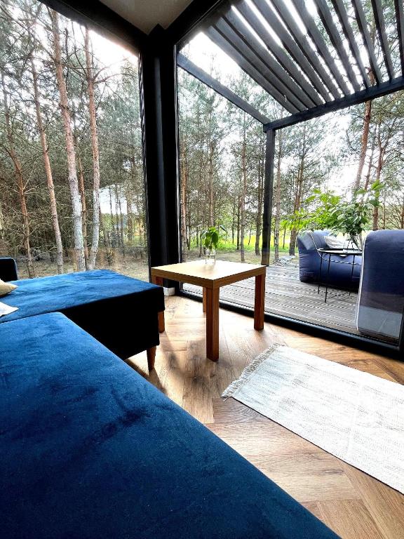 a room with two beds and a table and a large window at Przeszklony Tiny House w Lesie in Tomczyn
