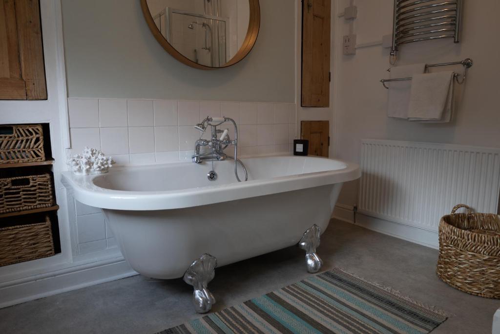 a white bath tub in a bathroom with a mirror at Chester Townhouse inside Roman Walls in Chester