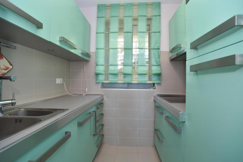 una cucina con armadi blu e lavandino di Panoramatic apartment a Petrovac na Moru