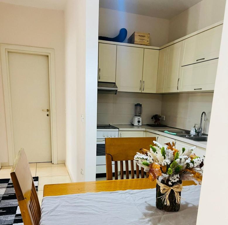 a kitchen with a table with a vase of flowers at KRISTO Apartment-Tirane in Tirana