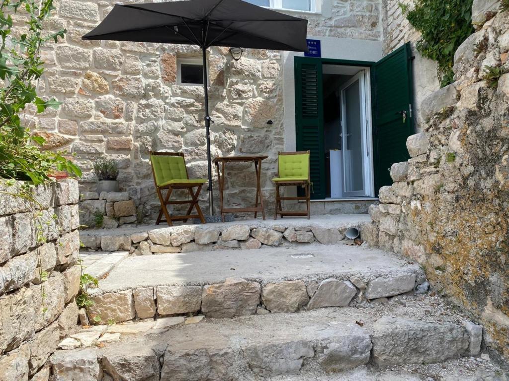 eine Terrasse mit 2 Stühlen und einem Tisch mit einem Sonnenschirm in der Unterkunft Studio Mirjana in Prvić Luka