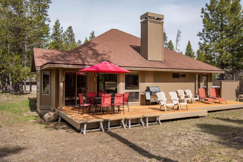 Casa con terraza con sillas y sombrilla roja en Plover 5 en Sunriver