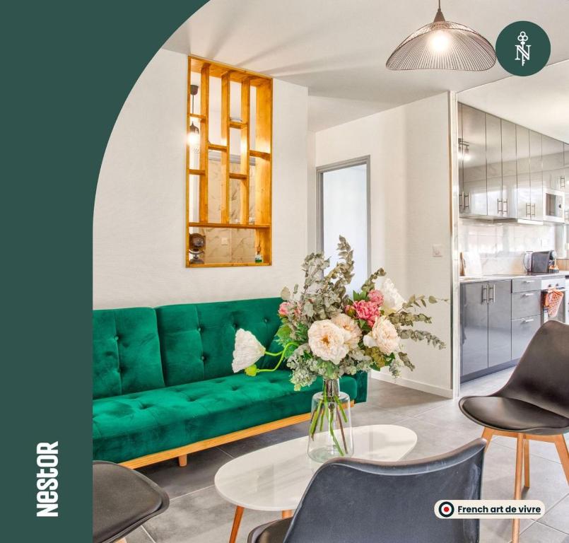 un sofá verde en una sala de estar con un jarrón de flores en La Casa Will - Family flat for 8, en Hérouville-Saint-Clair