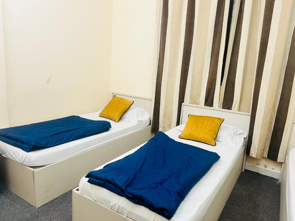 two beds with blue and yellow pillows in a room at Short Term Tourist Place in Dubai