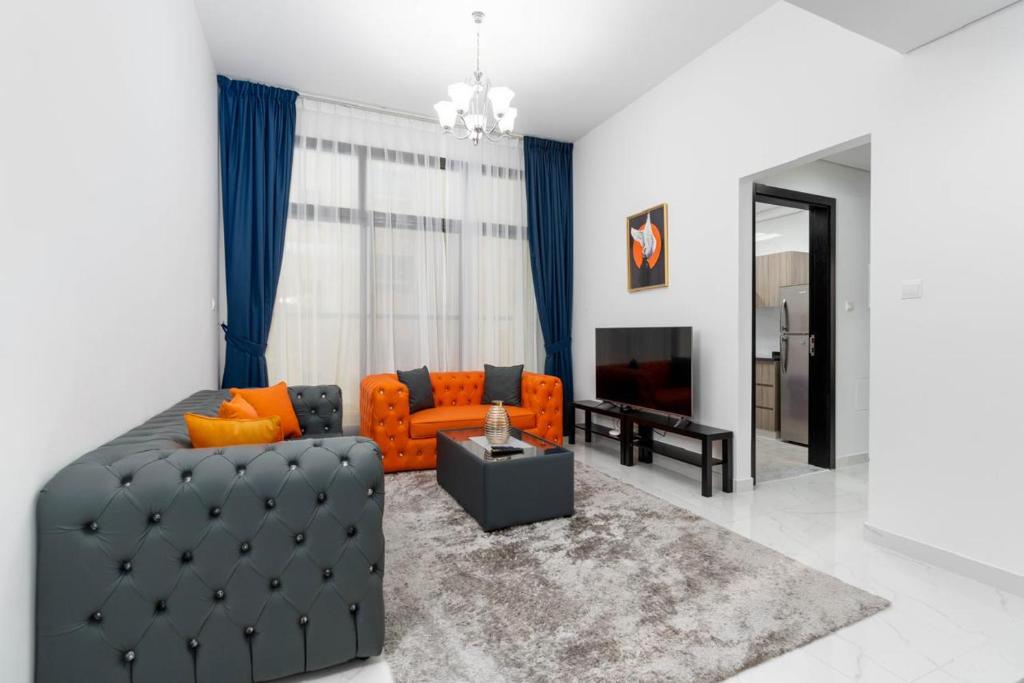 a living room with an orange couch and a television at Luxury Hotel Apartment Mall of Emirates in Dubai