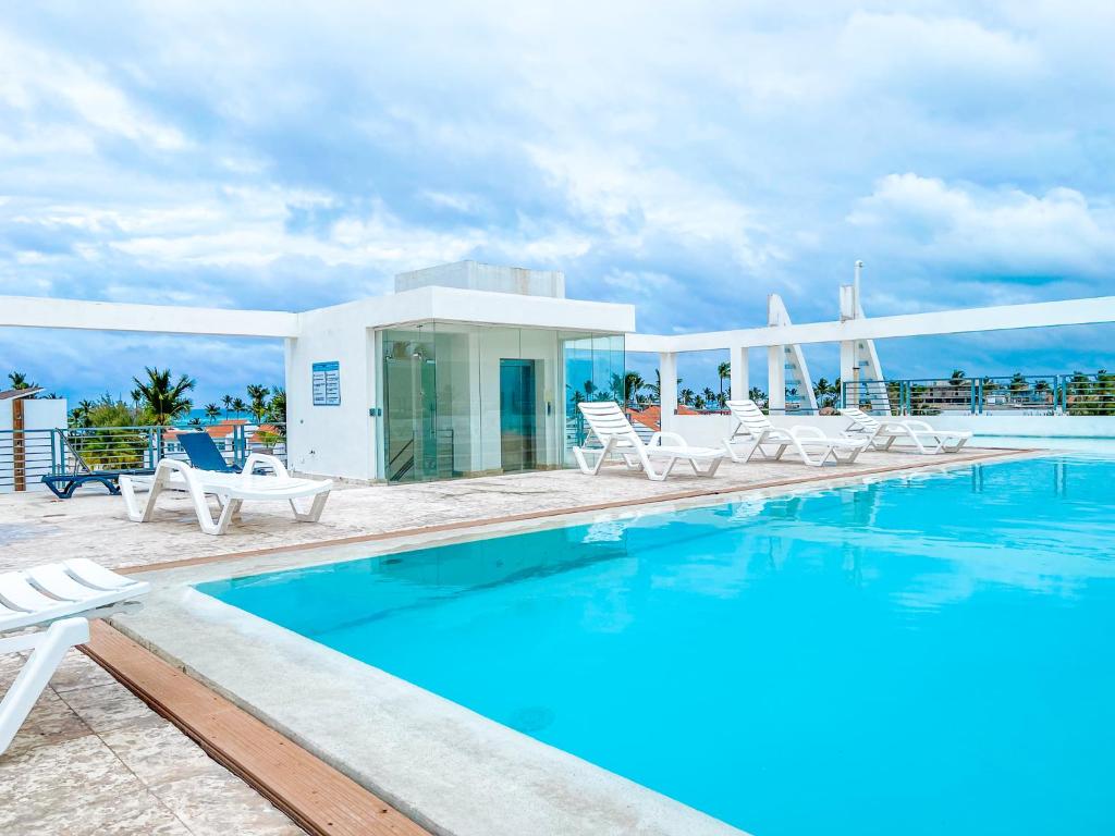 una piscina con sillas y una casa en DUCASSI Suites ROOMS & BEACH - playa Bavaro - WiFi - Parking - ROOFTOP POOL & SPA  en Punta Cana