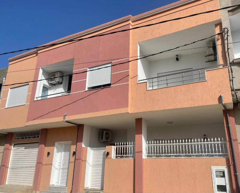 un bâtiment rose avec des fenêtres et des balcons blancs dans l'établissement Deluxe apartment, à Kelibia