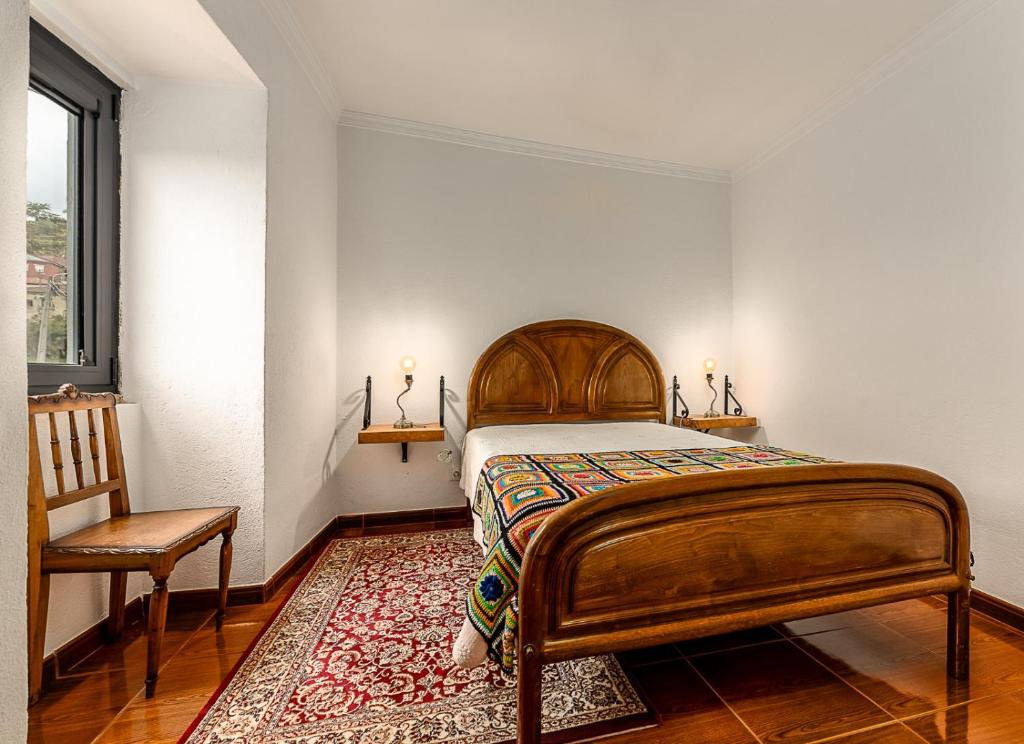 een slaapkamer met een houten bed en een stoel bij Casa dos Bardos in Alvações do Corgo