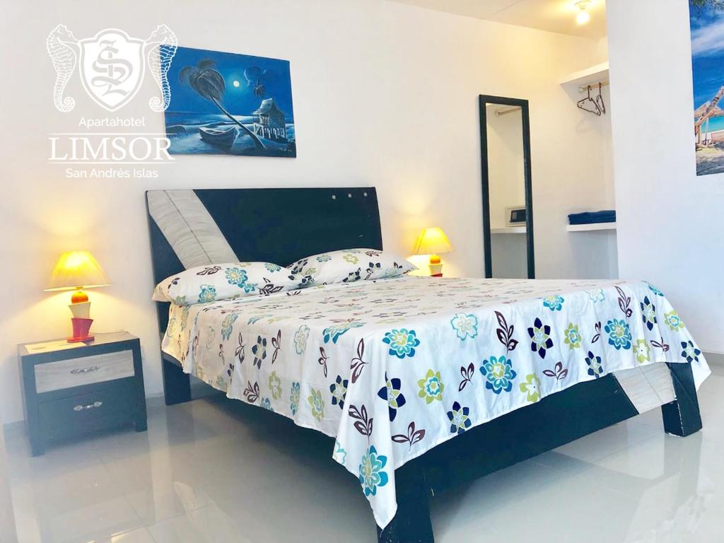 Schlafzimmer mit einem Bett mit einer weißen und blauen Bettdecke in der Unterkunft Limsor Aphotel in San Andrés