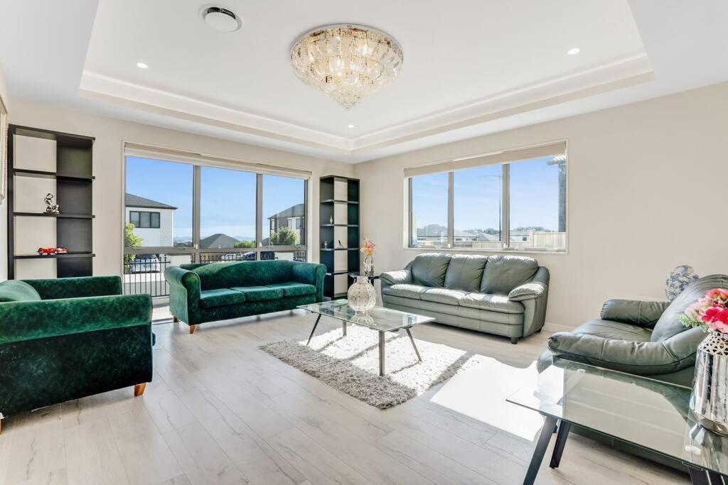 un soggiorno con mobili verdi e lampadario a braccio di 5 BDR Flat Bush Mansion - Central Aircon, Fast WiFi, Pool Table, Netflix and More! ad Auckland